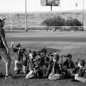 grayscale photo of boys football team in front of coach